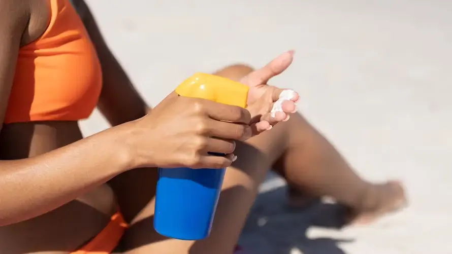 Image d'une femme noire avec de la crème solaire dans un flacon bleu